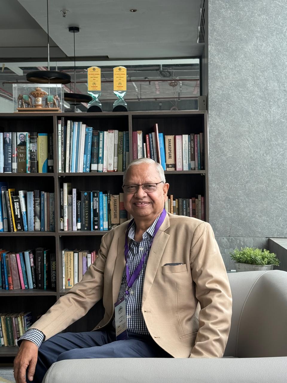 Dr. Parmanand N. Jain seated before a library bookshelf at a medical conference